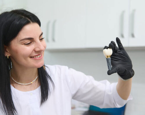 young woman holding dental implant mockup, artificial tooth roots into jaw canal. dental treatment concept